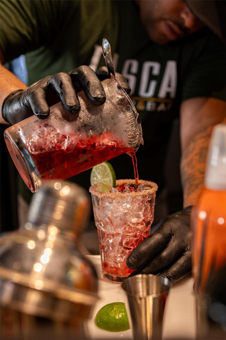 A bartender pouring a cocktail during a mixology session